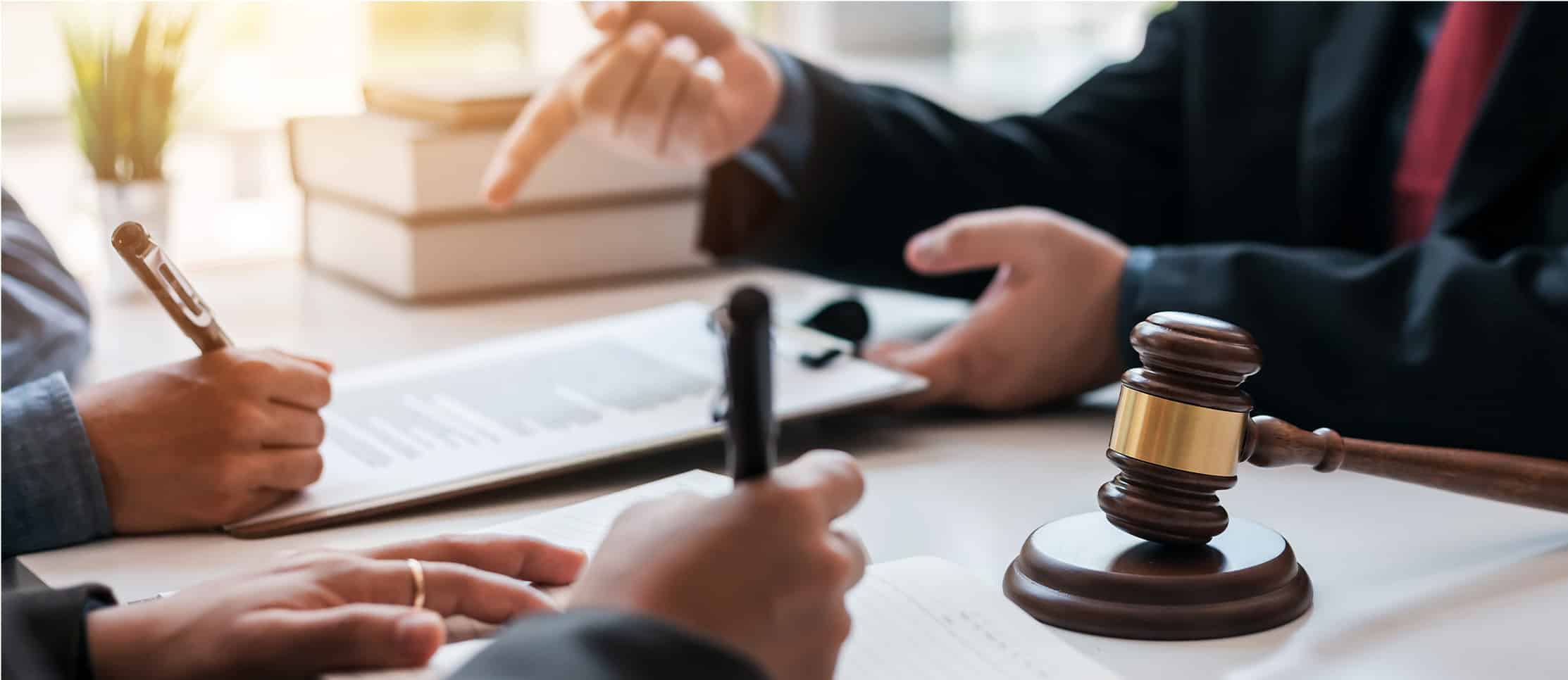 An attorney pointing to legal documents during a client consultation at a desk with a wooden gavel, representing DUI Lawyer Gaylord MI services.