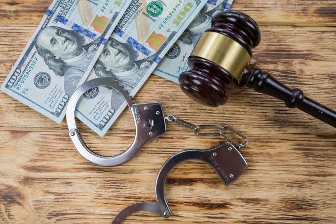 Handcuffs, US dollar bills, and a wooden gavel on a table, representing DUI Lawyer Gaylord MI legal services.