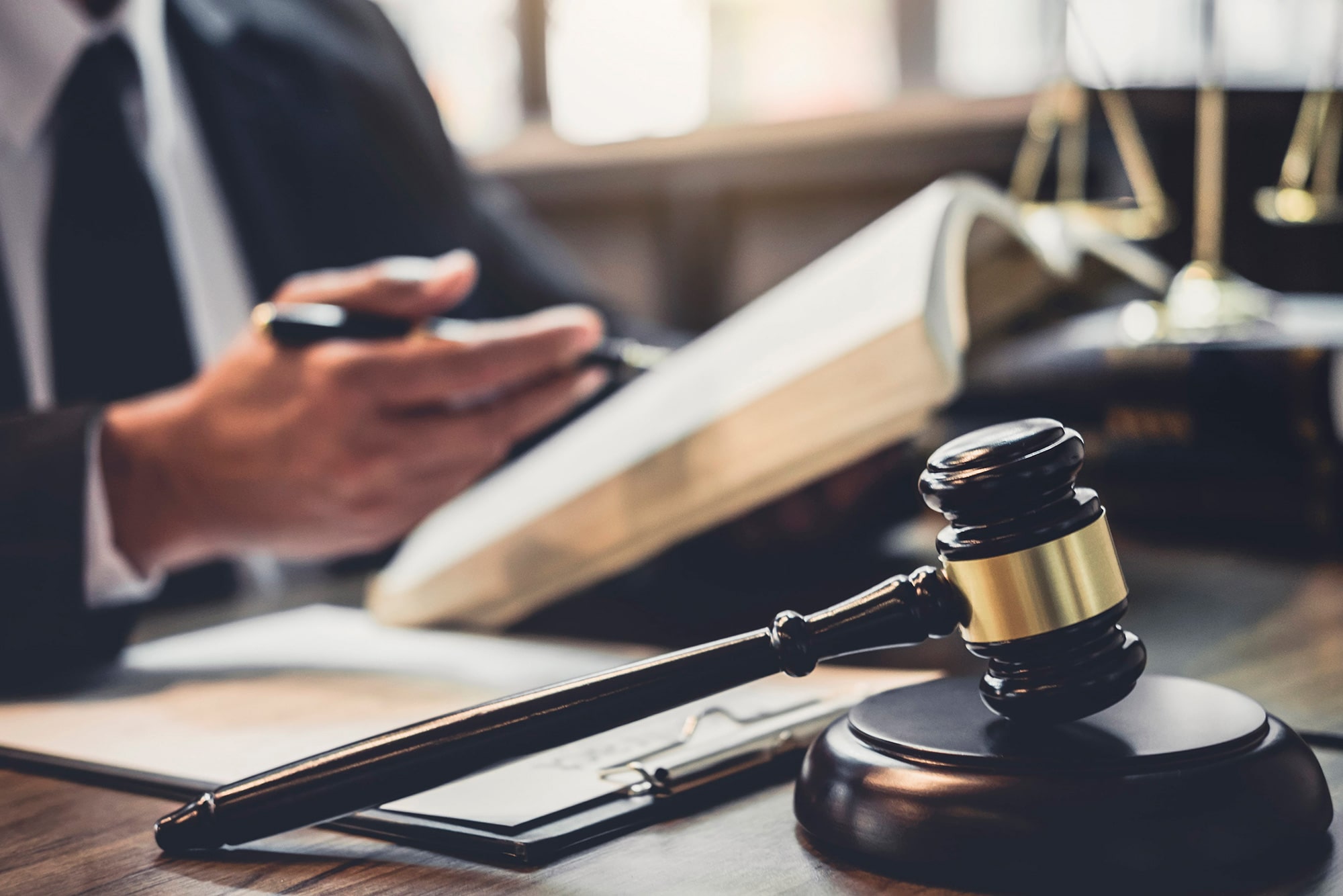 An attorney reviewing a law book at a desk with a wooden gavel in the foreground, representing DWI Lawyer Gaylord MI services.