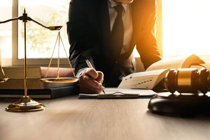 An attorney writing on legal documents at a desk with scales of justice and a gavel, representing OWI Lawyer Gaylord MI services.