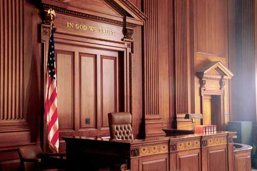 An empty courtroom with a wooden judge's bench and an American flag, representing OWI Lawyer Gaylord MI services.