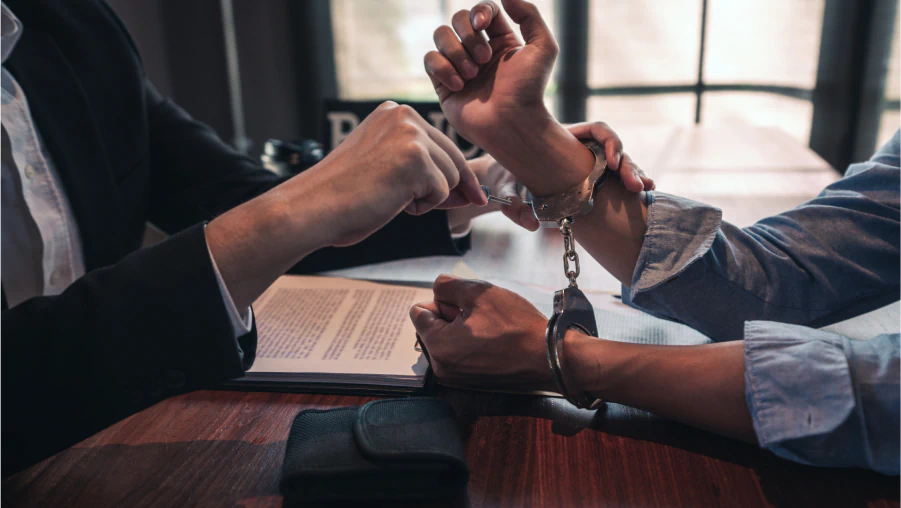 Close-up of an attorney unlocking handcuffs from a client's wrists over a desk, demonstrating the support of a skilled DUI Criminal Defense Attorney.