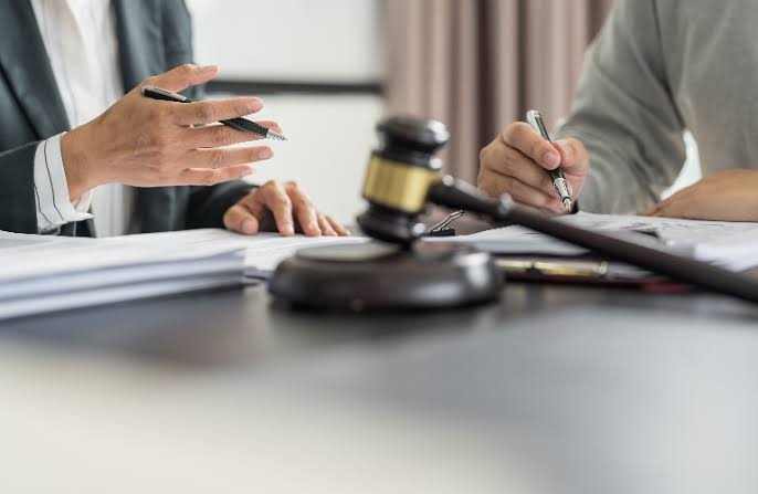 A lawyer reviewing legal paperwork with a client next to a gavel, representing a First Offense OWI Lawyer.