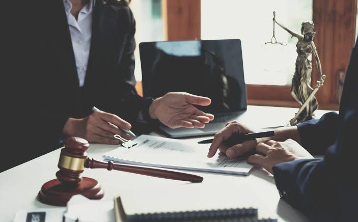 A defense lawyer explaining legal documents on a desk with a gavel and Lady Justice statue while assisting a client with an owi causing injury offense.